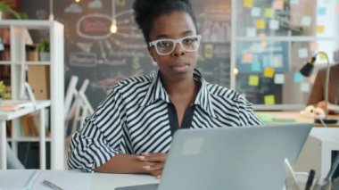 Ofiste oturan Afrikalı Amerikalı genç bir kadının yavaş çekim portresi.