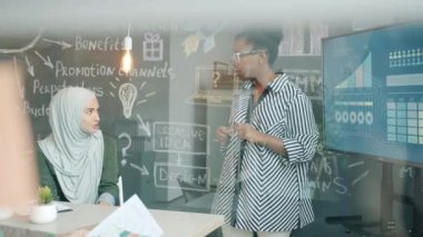 Ofiste sunum sırasında fikir alışverişinde bulunan çok ırklı bir grup genç insan