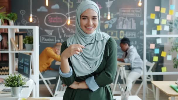 Slow motion porträtt av söt blandras dam i hijab stående i office leende — Stockvideo