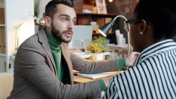 Un bell'uomo caucasico sta parlando con una collega afro-americana che parla di affari. — Video Stock