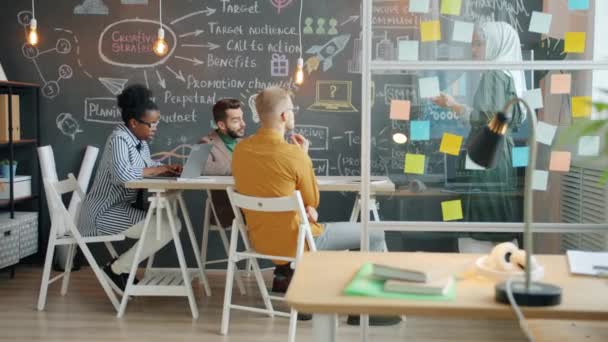 Équipe commerciale créative à l'écoute de la femme musulmane faisant une présentation au bureau avec mur de tableau noir — Video