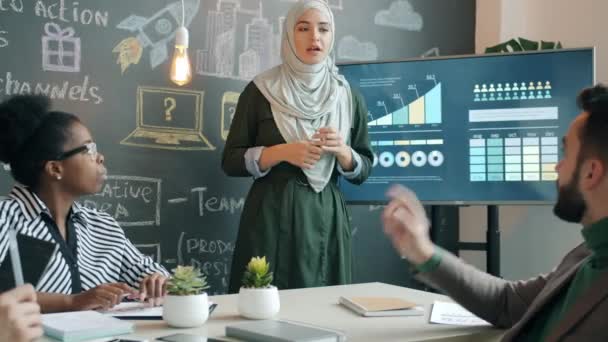Empleado musulmán motivado explicando ideas de negocios a un grupo de colegas en la oficina creativa — Vídeos de Stock