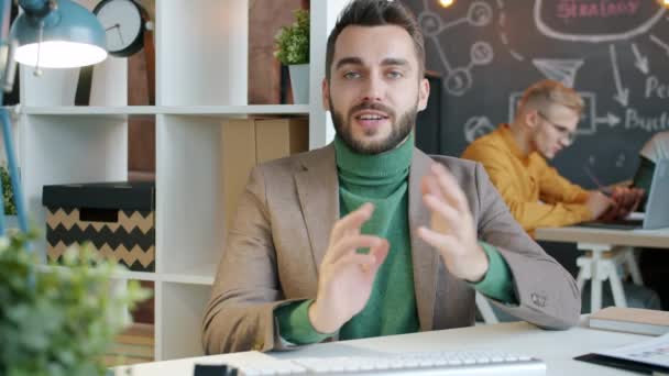 Молодий красивий бізнесмен робить відео дзвінок в офіс обговорення проекту онлайн — стокове відео