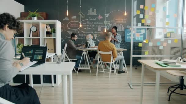 Zoom-in de mujer afroamericana confiada haciendo entrenamiento corporativo para el equipo de negocios en la oficina — Vídeos de Stock