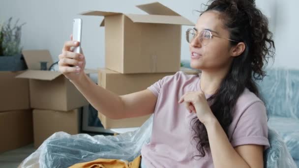 Fröhliche Asiatin diskutiert bei Videotelefonie mit Smartphone über Umzug in neue Wohnung — Stockvideo