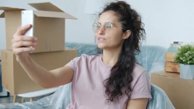 Yeni daireye taşınırken görüntülü konuşma yapan sevimli melez kadın.