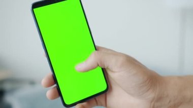 Erkek elinin kapalı alanda yeşil akıllı telefon ekranı araklamasının yavaş çekimleri
