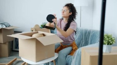 Sevimli melez bayan taşınma sırasında karton kutudan kişisel eşyalarını boşaltıyor.