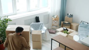 Genç nakliyecinin modern apartmana karton kutular taşıdığı yüksek açılı bir manzara.