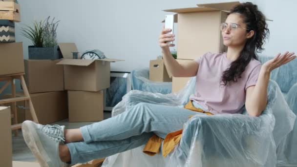 Hermosa chica asiática mostrando nueva casa durante la videollamada hablando en línea apuntando a cajas — Vídeos de Stock