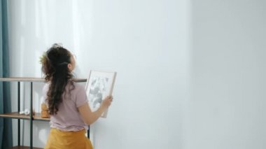 Yeni modern dairenin duvarına asılı yaratıcı kadının yavaş çekimleri.