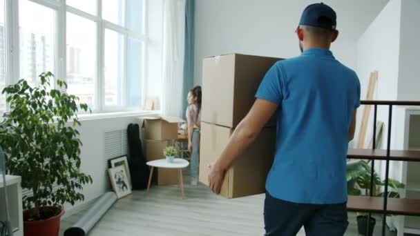 Langzame beweging van de werknemer in uniform brengen kartonnen dozen en praten met huiseigenaar binnen — Stockvideo