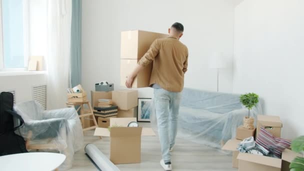 Movimiento de movimiento lento de tipo árabe que lleva cajas de cartón en apartamento moderno — Vídeo de stock