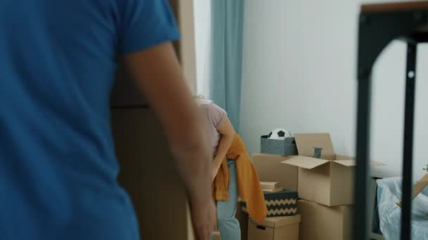 Ung kvinna packar upp tillhörigheter medan flyttaren tar med pappkartonger — Stockvideo