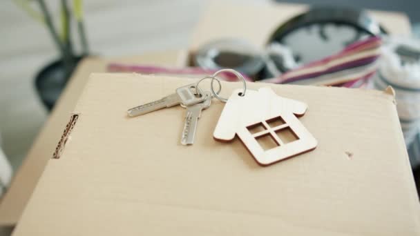 Närbild av nycklar till ny lägenhet på pappkartong inomhus i ljust rum — Stockvideo
