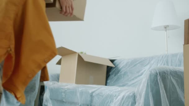 Primer plano de las manos de las mujeres poniendo caja de cartón en los muebles embalados durante la reubicación — Vídeo de stock