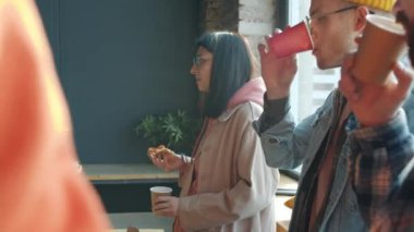 Modern ofiste pizza yiyen, konuşan ve gülen bir grup çalışan.