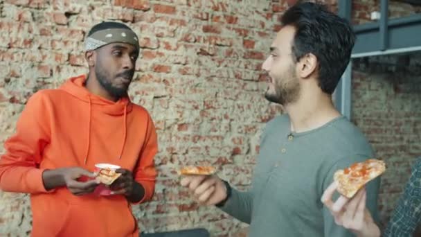 Empresários afro-americanos e árabes desfrutam de pizza e conversam em ambientes fechados no escritório moderno — Vídeo de Stock