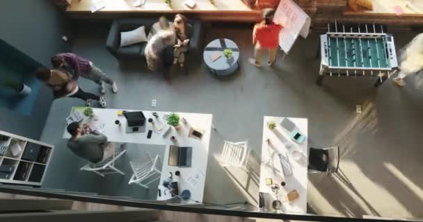 Вид зверху проміжок часу групи співробітників, які працюють і грають в настільні види спорту в сучасному офісі відкритого космосу — стокове відео