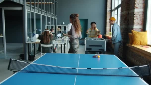 Mladí ambiciózní podnikatelé pracující ve sdílené kanceláři, zatímco kolegové hrají foosball — Stock video