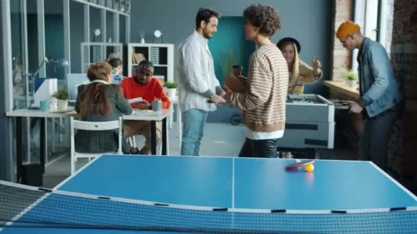 Mladá podnikatelka přichází do úřadu, zatímco kolegové hrají foosball a pracují — Stock video