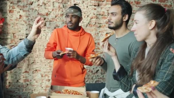 Vrolijke mannen en vrouwen genieten van pizza en zorgeloos gesprek in modern gedeeld kantoor — Stockvideo