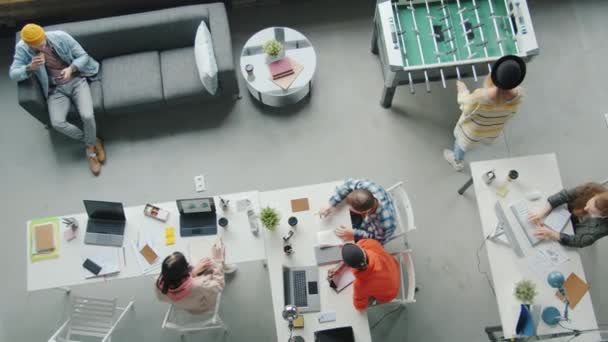 Top view alkalmazottak dolgoznak és csocsóznak a modern nyílt tér irodájában — Stock videók