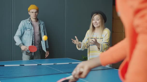 Бізнесмени грають в пінг-понг в сучасному офісі в той час як жінка-колега вітає — стокове відео