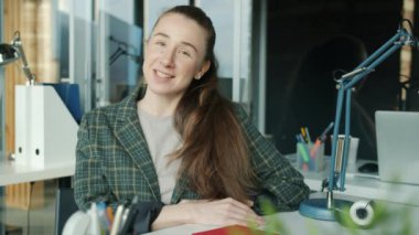 Genç iş kadını konuşuyor ve kameraya bakıyor. İnternetten video görüşmesi yapıyor.