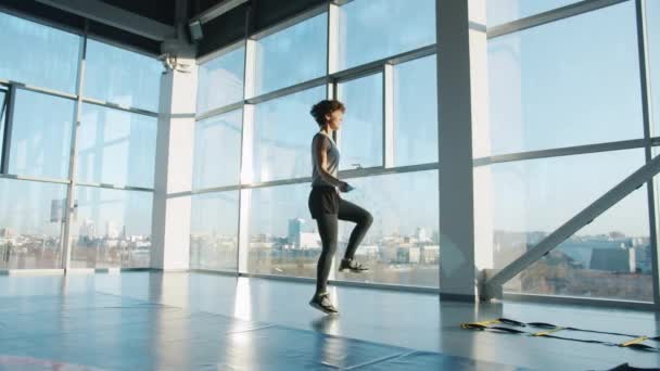 Zpomalený pohyb štíhlé sportovkyně cvičení s skákacím lanem v moderní tělocvičně — Stock video