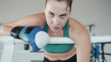 Boks eldiveni giyen yorgun genç boksörün yavaş çekimde çekilmiş portresi.