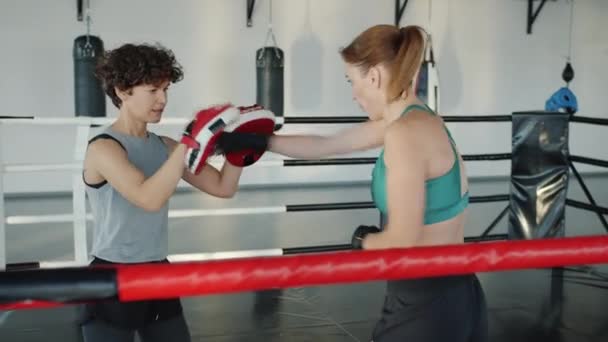 Perempuan kickboxer berlatih dengan instruktur meninju dan menendang berkonsentrasi pada latihan — Stok Video