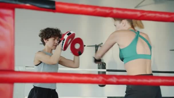 Jovem mulher kickboxing com treinador feminino praticando chutes e socos no ginásio — Vídeo de Stock