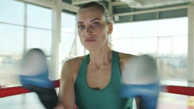 Saldırgan kadın boksör yumruk hareketi yapıyor sonra da ciddi bir yüzle kameraya bakıyor.