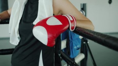 Boks ringinin köşesinde eldivenlerle duran yorgun dövüşçünün yavaş çekim portresi.