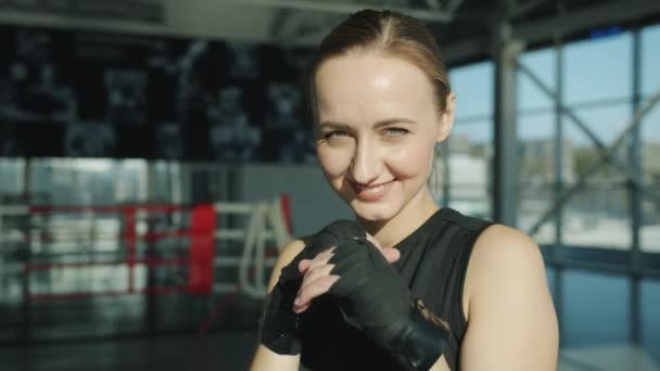 Veselá mladá sportovkyně s ovinutýma rukama stojící v tělocvičně a usmívající se do kamery — Stock video
