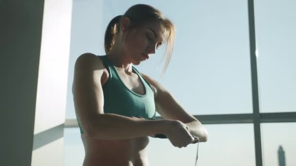 Attractive female fighter wrapping hands before training standing in sunlit gym — Stock Video