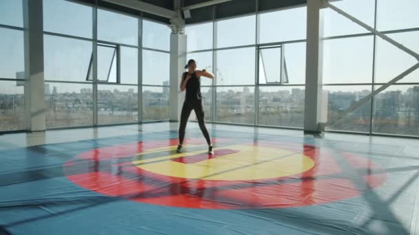 Combate de kickboxing femenino entrenando solo en gimnasia practicando movimientos — Vídeo de stock