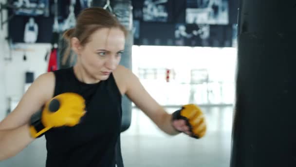 Motivovaná sportovkyně trénuje vinteriéru vmoderní posilovně bití boxovací pytel — Stock video