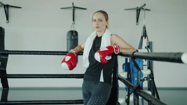 Slow motion porträtt av trött flicka fighter bär handskar stående i boxningsringen — Stockvideo