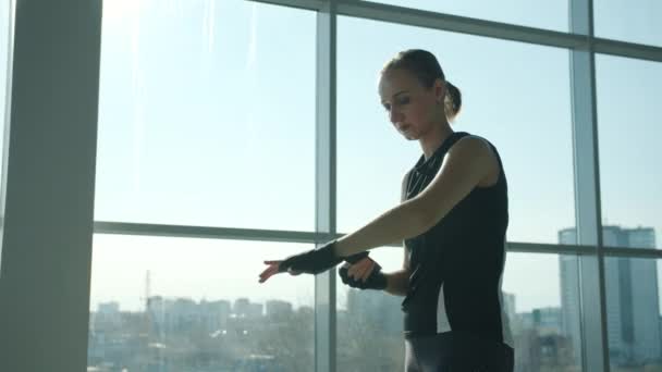 Fiducioso pugile femminile che avvolge le mani con cinghie e poi pratica i movimenti delle braccia in palestra — Video Stock