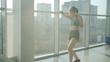 Şehir jimnastik salonunda cam duvarlarla tek başına antrenman yapmaya odaklanmış çekici bir kız.