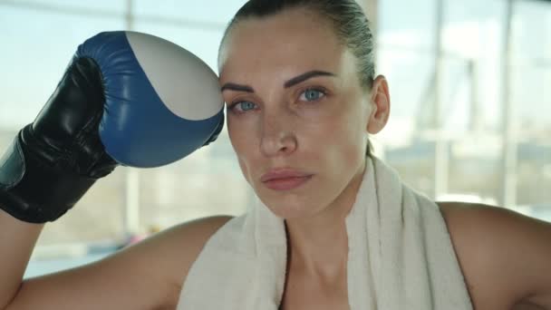 Retrato de cerca de una hermosa luchadora joven usando guantes de boxeo y toalla de pie en el gimnasio — Vídeo de stock