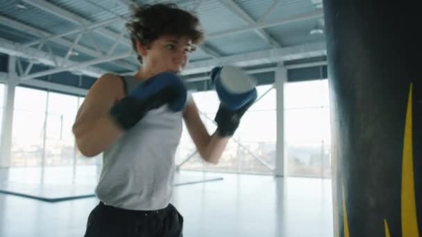 Movimiento lento de boxeo femenino motivado con saco de boxeo haciendo ejercicio solo en el gimnasio — Vídeo de stock