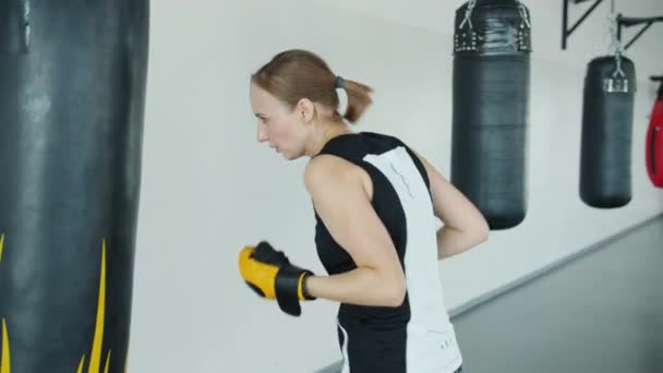 Ajuste deportista haciendo ejercicio en gimnasio golpeando saco de boxeo entrenamiento solo — Vídeo de stock