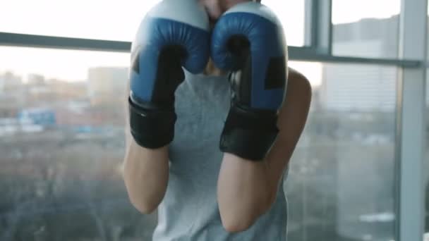 Boxer feminino motivado usando luvas olhando para a câmera e dando socos pulando no ginásio — Vídeo de Stock