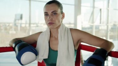 Eldiven takarak ringin köşesinde dinlenen başarılı bir boksörün yavaş çekim portresi.