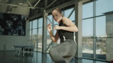 Spor giyimli genç bir kadının portresi modern spor salonunda kickboks hareketleri yapıyor.