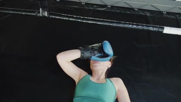 Vedere de sus a obosit și transpirat tânără femeie MMA luptător culcat pe podea în sala de gimnastică relaxare — Videoclip de stoc