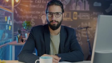 Akşamları ofiste oturan dalgın Orta Doğulu bir adamın yavaş çekim portresi.